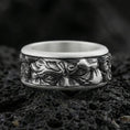 Load image into Gallery viewer, Oxidized sterling silver Michelangelo Moses spinner band ring on dark volcanic rock, Renaissance-inspired face relief on rotating center, premium macro product shot.