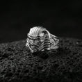 Load image into Gallery viewer, Sterling silver Egyptian mummy mask statement ring in a polished silver finish, sculpted monster face with striped pharaoh-style headpiece, close-up on volcanic stone