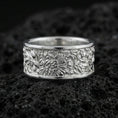 Load image into Gallery viewer, Polished silver nature wildlife engraved band ring on black volcanic stone, crisp botanical relief with detailed jungle scene texture, centered close-up studio lighting.