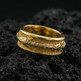 Load image into Gallery viewer, Gold plated arrow spinner band ring on volcanic rock, detailed arrow motif on rotating band with rustic hammered texture, luxury jewelry product photography.