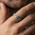 Load image into Gallery viewer, Oxidized sterling silver faceted band worn on finger, bold chevron-cut texture with dark recessed grooves, lifestyle hand close-up.