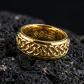 Load image into Gallery viewer, Gold plated Celtic knot woven band ring on volcanic rock, bold raised braid texture with high-contrast depth, luxury studio macro image.