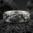 Load image into Gallery viewer, Oxidized sterling silver wolf and deer band ring on black volcanic rock, high-relief animal heads with deep shadowed texture, sharp macro product photo.
