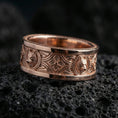 Load image into Gallery viewer, Rose gold plated wolf Celtic band on black volcanic stone, detailed wolf medallions with warm shine and high-relief texture, elegant product photo.