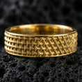 Load image into Gallery viewer, Gold plated woven-grid textured ring on volcanic rock, warm metallic sheen across the geometric pattern, high-contrast studio macro.