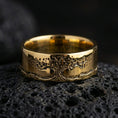 Load image into Gallery viewer, Gold plated Tree of Life band ring on black volcanic stone, warm shine accenting the engraved tree silhouette and landscape border, studio macro.