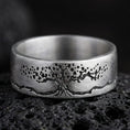Load image into Gallery viewer, Oxidized sterling silver Tree of Life band ring on black volcanic stone, darkened engraved branches and roots for strong contrast, macro product photo.