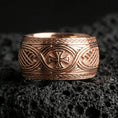 Load image into Gallery viewer, Rose gold plated Celtic weave ring with iron cross motif on volcanic rock, soft warm tone highlighting the engraved knot panels and raised emblem.