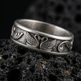 Load image into Gallery viewer, Sterling silver swan band ring photographed on volcanic rock with oxidized contrast bringing out the carved wings and textured background.