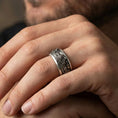 Load image into Gallery viewer, Oxidized sterling silver wolf spinner ring worn on a finger, showcasing the rotating band and high-relief wolf detailing.