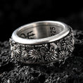 Load image into Gallery viewer, Sterling silver floral spinner ring photographed on volcanic rock with oxidized contrast highlighting the daisy blossoms and engraved petals.