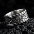 Load image into Gallery viewer, Sterling silver ornate scroll ring photographed on volcanic rock with oxidized contrast highlighting the engraved filigree and textured center band.