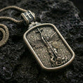 Load image into Gallery viewer, Saint Michael dog tag pendant on black volcanic stone with bronze material, showing the archangel with spear and shield.