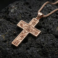 Load image into Gallery viewer, Rose gold plated Christian cross pendant with detailed rose accents resting on volcanic rock in an elegant close-up product presentation