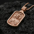 Load image into Gallery viewer, Rose gold plated devotional Jesus pendant with Sacred Heart motif, halo detail, and framed silhouette resting on volcanic rock in an elegant close-up product presentation