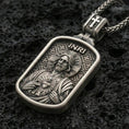 Load image into Gallery viewer, Oxidized Sacred Heart Jesus pendant with INRI detail and framed devotional portrait displayed on dark volcanic rock in a close-up luxury jewelry composition