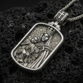 Load image into Gallery viewer, Oxidized Virgin Mary and Child pendant with crowned Madonna relief displayed on dark volcanic rock in a close-up luxury jewelry composition