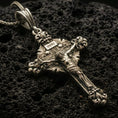 Load image into Gallery viewer, Bronze crucifix pendant with INRI plaque, detailed Jesus figure, and ornate baroque cross design displayed on dark volcanic rock in a close-up luxury jewelry composition