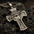 Load image into Gallery viewer, Bronze Jesus crucifix pendant with crown of thorns, INRI inscription, and sculpted face relief displayed on dark volcanic rock in a close-up luxury jewelry composition