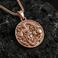 Load image into Gallery viewer, Sterling silver dragon medallion pendant with a rose gold plated finish, round high-relief dragon design with dramatic depth, macro on black volcanic rock