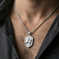 Load image into Gallery viewer, Sterling silver winged lion crest pendant necklace on the neck, macro lifestyle image showing the polished silver finish and shield silhouette