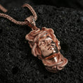 Load image into Gallery viewer, Rose gold plated Medusa head pendant necklace on textured volcanic rock, close-up centered product photo with refined shine across the Medusa face and serpent wrap.