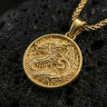 Load image into Gallery viewer, Gold plated round dragon coin pendant necklace on textured volcanic rock, premium close-up shot with warm reflective shine across the dragon design and raised border.
