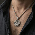 Load image into Gallery viewer, Oxidized round dragon coin pendant necklace worn on the neck, lifestyle framing showing realistic size and bold darkened relief against the chest.
