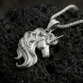 Load image into Gallery viewer, Polished silver unicorn head pendant necklace on textured volcanic rock, crisp macro product photo emphasizing bright reflections, clean edges, and sculpted mane detail.