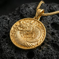 Load image into Gallery viewer, Gold plated oriental dragon medallion pendant necklace on textured volcanic rock, premium close-up with warm reflective shine across the dragon head, scales, and raised border.