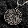 Load image into Gallery viewer, Oxidized dragon medallion pendant necklace on textured volcanic rock, centered close-up highlighting the coiled dragon, swirling cloud motifs, and deep antique shadowed contrast.