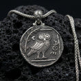 Load image into Gallery viewer, Oxidized owl coin pendant necklace on textured volcanic rock, centered close-up highlighting the ancient-style owl relief, moon detail, and deep antique contrast on the matte background.