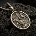 Load image into Gallery viewer, Bronze resurrection medal pendant with risen Christ, cross staff, and halo detail displayed on dark volcanic rock in a close-up luxury jewelry composition