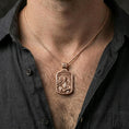 Load image into Gallery viewer, Rose gold plated Archangel Gabriel pendant with winged figure and saint inscription worn on the neck in a refined lifestyle shot with a warm and elegant presentation