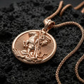 Load image into Gallery viewer, Rose gold plated Saint George pendant with horse rider relief, circular silhouette, and symbolic battle scene resting on volcanic rock in an elegant close-up product presentation