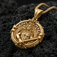 Load image into Gallery viewer, Gold plated Saint Michael necklace with detailed winged guardian, sword motif, and circular devotional design showcased on black volcanic rock in a refined macro jewelry image