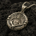 Load image into Gallery viewer, Bronze Saint Michael pendant with winged warrior figure, sword detail, and Saint Michael inscription displayed on dark volcanic rock in a close-up luxury jewelry composition