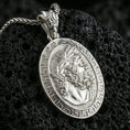 Load image into Gallery viewer, Polished silver Hades coin pendant necklace on textured volcanic rock, crisp macro product photo emphasizing clean edges, sharp beard-and-hair engraving, and bright reflective highlights on the relief.