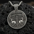Load image into Gallery viewer, Oxidized Viking deer medallion pendant necklace on textured volcanic rock, centered close-up highlighting the twin stag motif, carved knotwork column, and deep antique shadowed contrast.