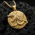 Load image into Gallery viewer, Gold plated Anubis medallion pendant necklace on textured volcanic rock, premium close-up with warm reflective shine across the jackal profile, raised hieroglyph ring, and sculpted contours.