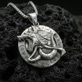 Load image into Gallery viewer, Polished silver Anubis medallion pendant necklace on textured volcanic rock, crisp macro product photo emphasizing clean edges, sharp hieroglyph symbols, and bright reflective highlights on the jackal relief.