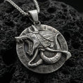 Load image into Gallery viewer, Oxidized Anubis medallion pendant necklace on textured volcanic rock, centered close-up highlighting the snarling jackal head, circular hieroglyph border, and deep antique shadowed contrast.