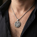 Load image into Gallery viewer, Polished silver geometric rune-style medallion pendant necklace worn on the neck, clean lifestyle wear shot capturing bright shine and the detailed labyrinth-like symbol in natural light.