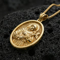 Load image into Gallery viewer, Gold plated Saint Francis pendant with sculpted religious figure, haloed portrait, and cross detail showcased on black volcanic rock in a refined macro jewelry image