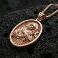 Load image into Gallery viewer, Rose gold plated oval Saint Francis necklace with sacred portrait relief, halo, and devotional cross resting on volcanic rock in an elegant close-up product presentation