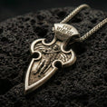 Load image into Gallery viewer, Bronze Saint Michael cross pendant with winged archangel figure, engraved Cyrillic inscription, and elongated gothic silhouette displayed on dark volcanic rock in a close-up luxury jewelry composition