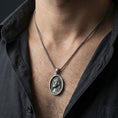 Load image into Gallery viewer, Oxidized Jesus Christ pendant with crown of thorns worn on the neck in a lifestyle jewelry shot, styled against the chest for a bold and devotional look