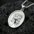 Load image into Gallery viewer, Polished silver Jesus medal with oval frame, crown of thorns, and sculpted devotional face placed on textured volcanic rock in a premium studio product shot