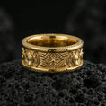 Load image into Gallery viewer, Gold plated fox band ring on textured volcanic rock, premium close-up with warm reflective shine across the fox head motifs and engraved ornamental frame.