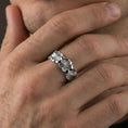 Load image into Gallery viewer, Polished silver floral band ring worn on a finger, clean lifestyle wear shot capturing bright shine and the detailed lily relief in natural light.